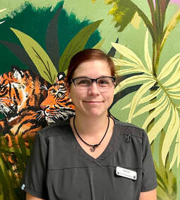 Picture of  Maggy staff member in front of jungle wall mural